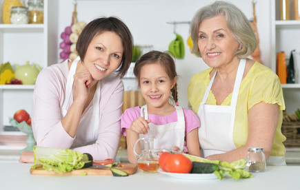 happy women with little girl cooking in kitchen