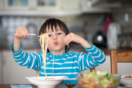 Cute little boy, eating spaghetti at home for lunchtime, tasty food