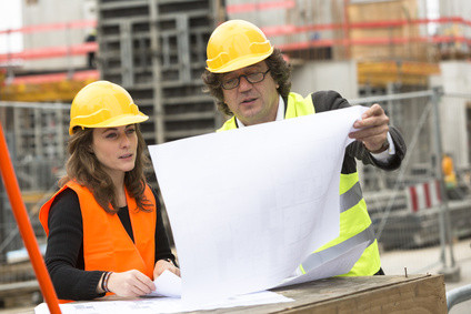 Two engineers on building site checking plans