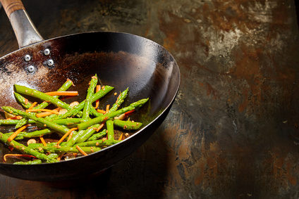 Healthy fresh green asparagus shoots cooked with diced carrots and savory seasoning served in an old rustic frying pan on a rusty metal surface with copy space