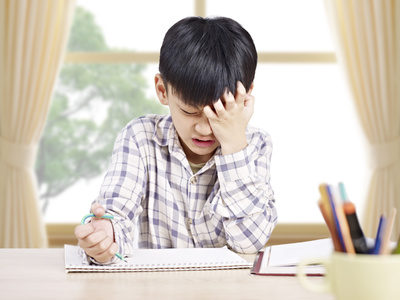 10 year-old asian elementary schoolboy appears to be frustrated while doing homework at home.