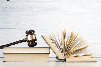 Law concept - Book with wooden judges gavel on table in a courtroom or enforcement office